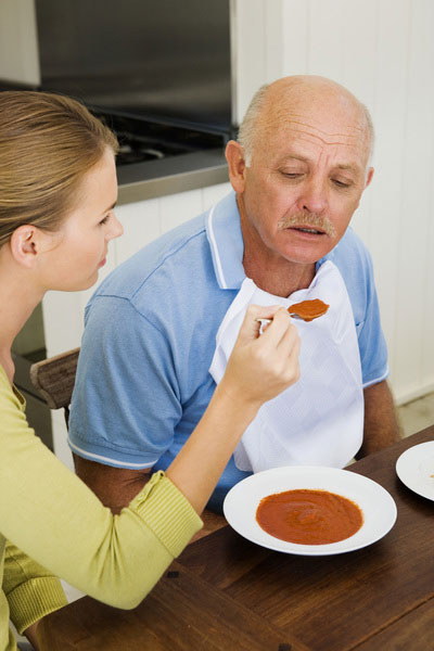 caregiver feeding an elderly man