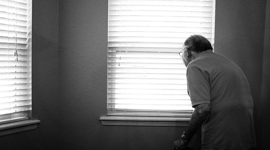 an old man in the room peeking through a window