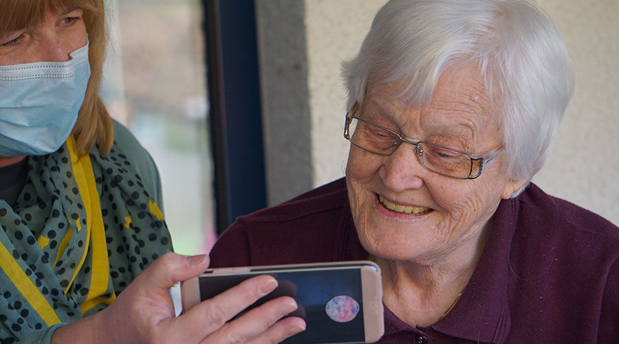 caregiver helps the elderly woman watch on the mobile phone