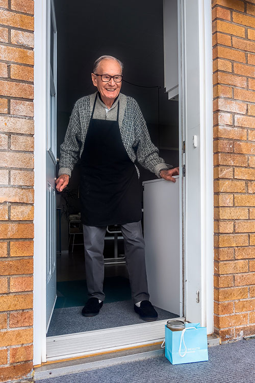 an elderly man getting his package in front of his house