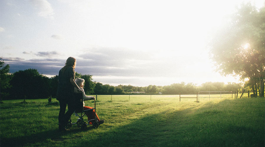 a caregiver assisting her elderly client on the backyard