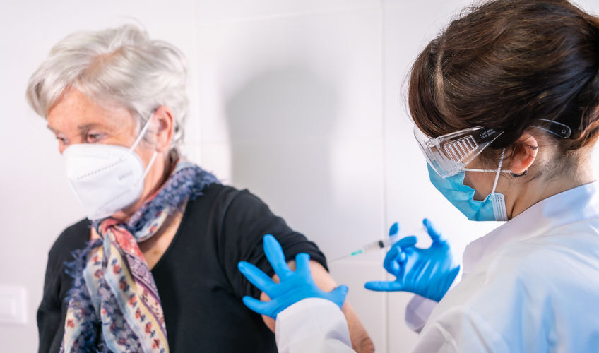 health worker administering vaccine to elderly woman