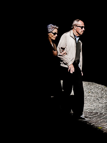 elderly couple holding each other while crossing on the street