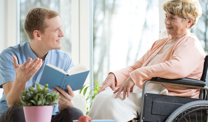 caregiver reading a book to elderly