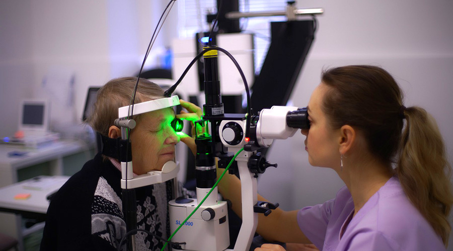 optician performing eye check up on elderly