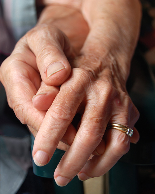 caregiver holding the hand of an elderly person