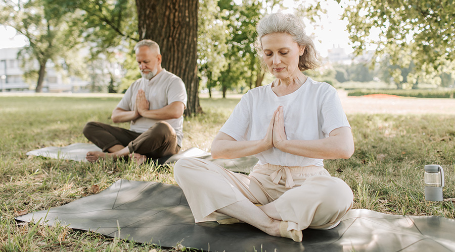 elderly couple doing breathing exercise at the park