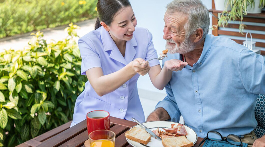 caregiver feeding elderly senior man