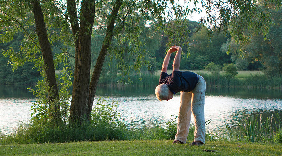 elderly person doing stretching beside the lake