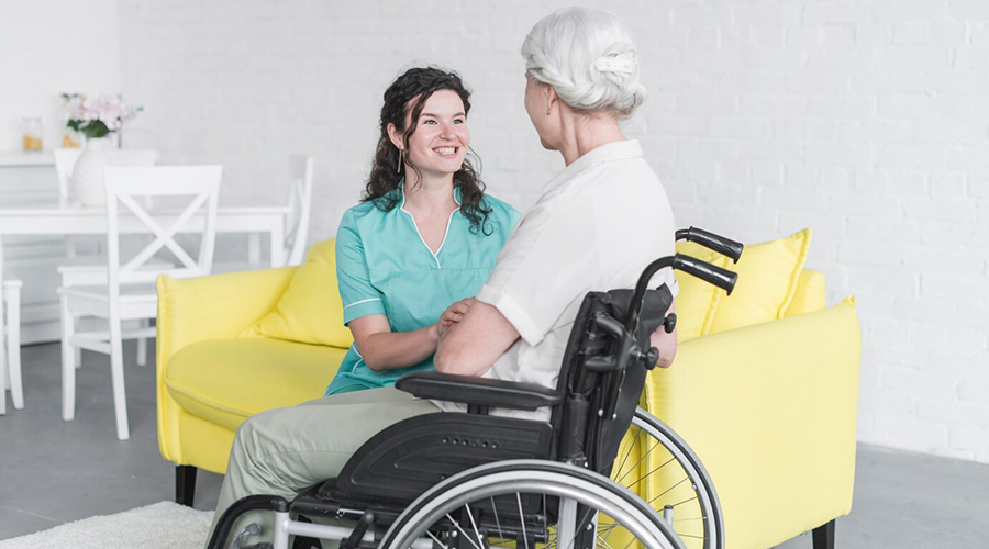 smiling woman looking senior woman sitting wheel chair