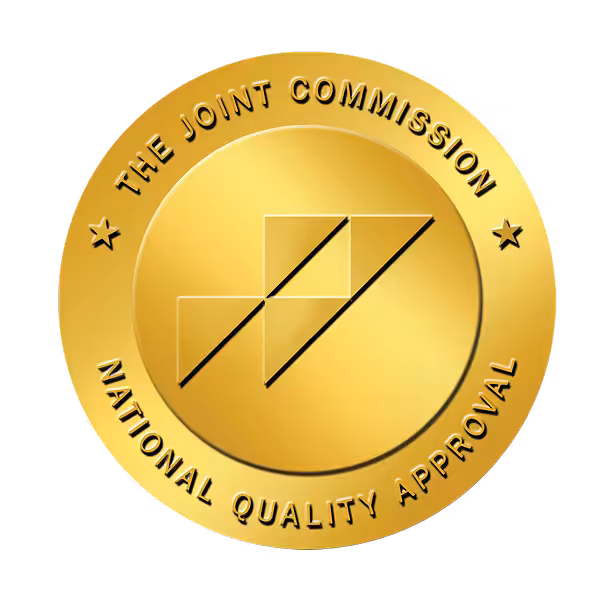 A gold circular seal with the text The Joint Commission National Quality Approval surrounding an abstract geometric logo in the center, symbolizing excellence in home care.